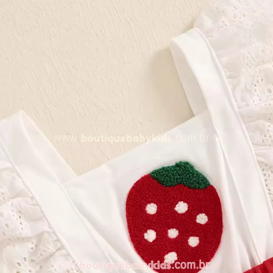 Detalhe do bordado de morango texturizado no romper branco e vermelho, com babados rendados nas alças.