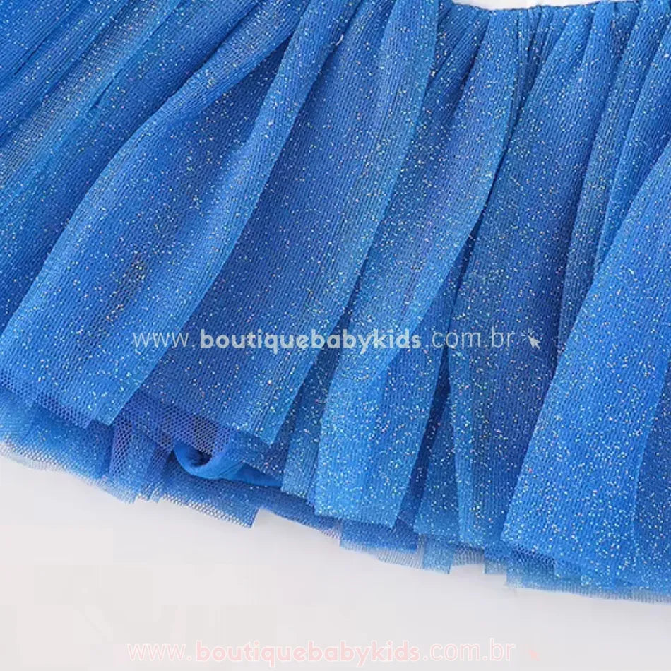 Detalhe da saia de tule azul com partículas brilhantes, criando um efeito cintilante encantador para um visual mágico.