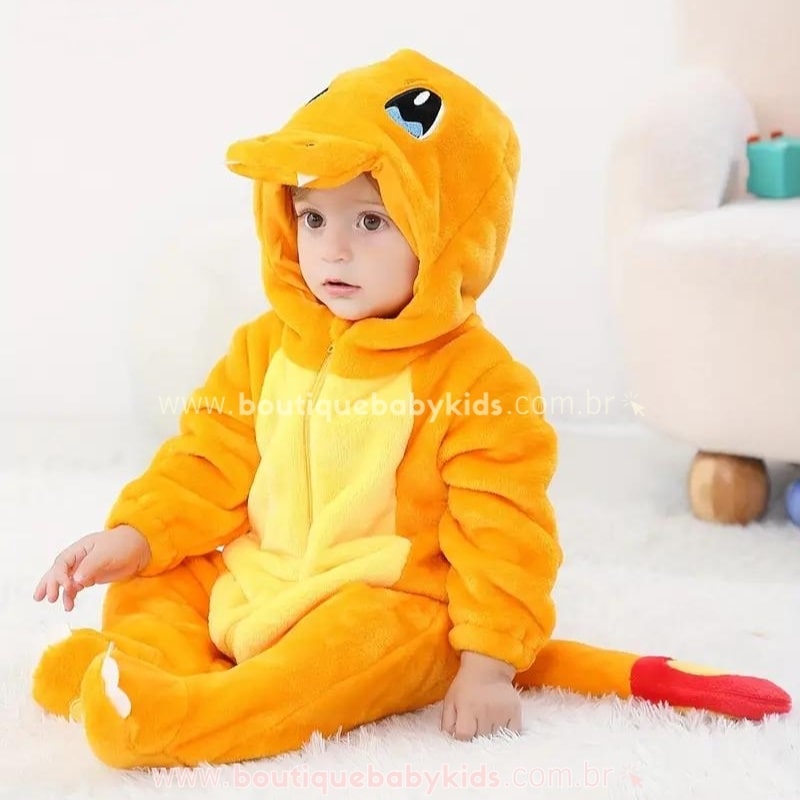 Bebê sentado no chão com capuz abaixado, vestindo o Macacão Bebê Fantasia Pokémon Charmander, destacando o design aconchegante e a cauda com chama estilizada.