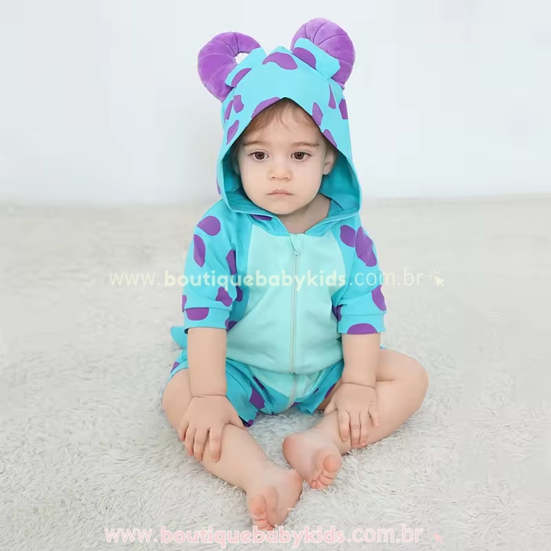 Bebê vestindo a fantasia do Sulley, com capuz ajustado, exibindo as cores vibrantes azul e roxo, com fecho frontal e tecido macio.