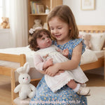 Menina sorrindo segurando a Boneca Bebê Reborn Stella no colo em um quarto infantil, demonstrando o tamanho real e o realismo da boneca comparada a uma criança.