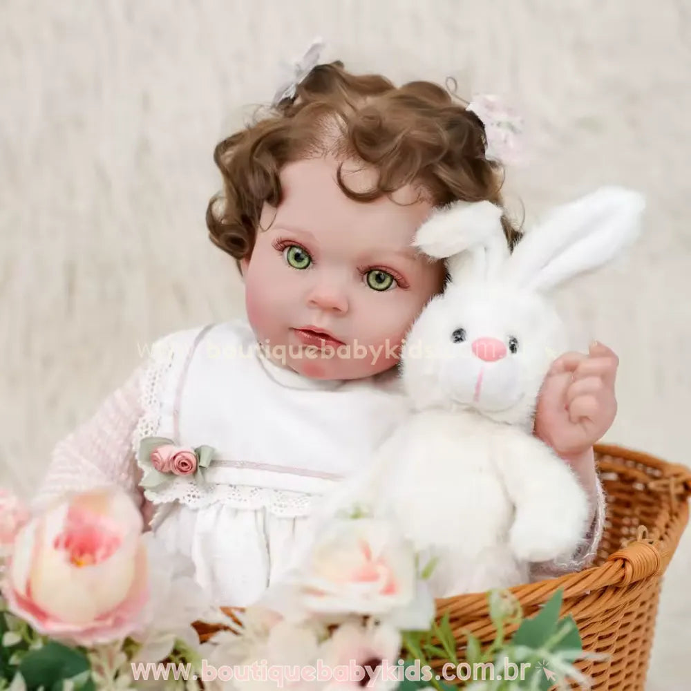Close-up do rosto da Boneca Bebê Reborn mostrando detalhes dos olhos verdes e cabelos castanhos cacheados, segurando um coelho de pelúcia branco próximo à bochecha.