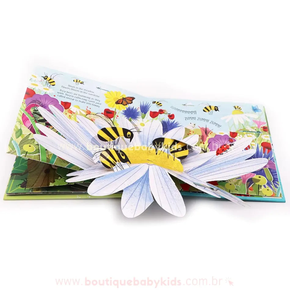 Página do livro Pop-Up Nature apresentando um campo florido com diversas abelhas pousando sobre uma grande margarida branca. As pétalas e os insetos saltam da página, criando um efeito dinâmico.