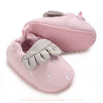 Par de pantufinhas de bebê de moranguinho rosa, com um dos pares virado para cima, revelando a sola antiderrapante pontilhada. 