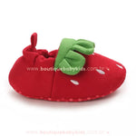 Perfil lateral da pantufinha vermelha de morango, evidenciando o acabamento elástico para melhor ajuste nos pés do bebê. 
